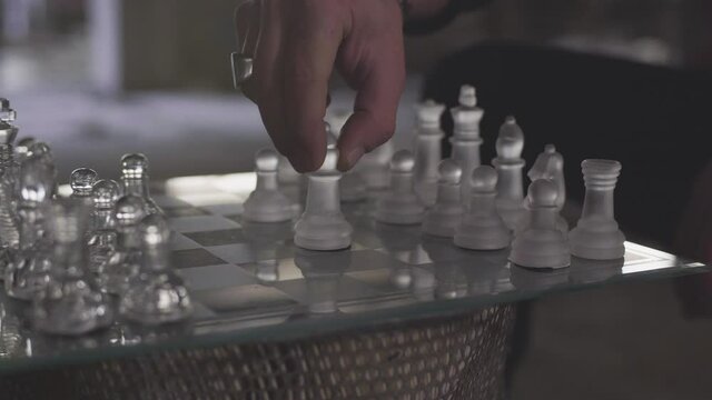 main homme joue au &eacute;checs en verre dans une piece sombre  