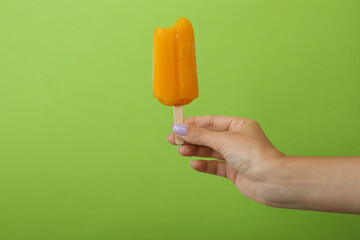 Female hand hold ice cream stick on green background