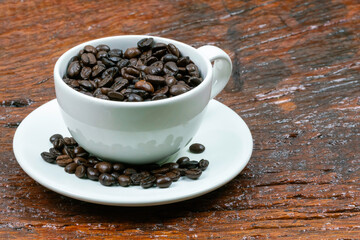 Roasted coffee beans and white coffee cup .