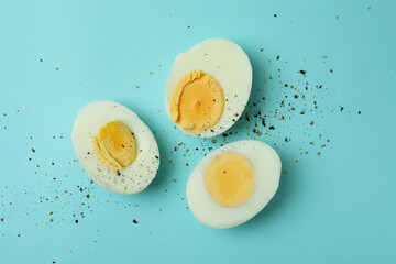 Tasty boiled eggs on blue background, top view