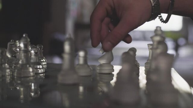 main homme joue au &eacute;checs en verre dans une piece sombre  
