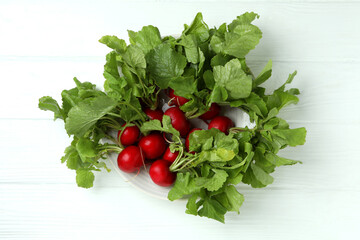 Plate with radish on white wooden background, top view