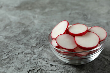 Bowl with chopped radish on gray textured background