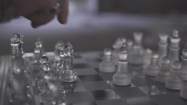 main homme joue au &eacute;checs en verre dans une piece sombre  