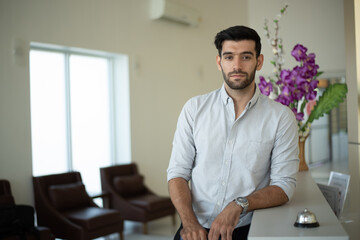 Business man using service bell on hotel reception desk.