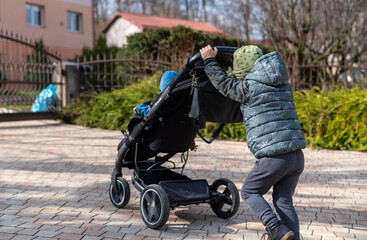 child pushing a stroller with a toddler in,  carriage