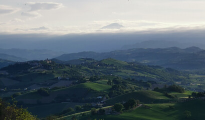 Fototapeta na wymiar Vallate verdi e colline illuminate dal sole e monti Appennini avvolti dalle nuvole