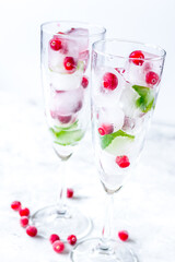 Ice cubes with berries and mint in glasses for summer drink white background