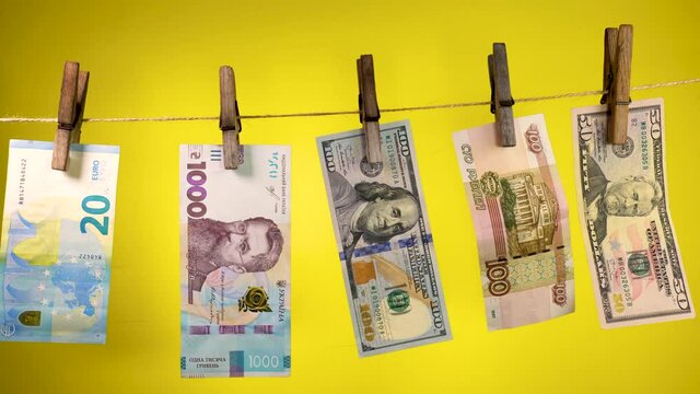 Banknotes of different countries dry on a clothespin rope