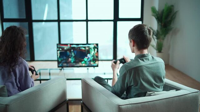 happy couple playing video game with controller on play station console at home