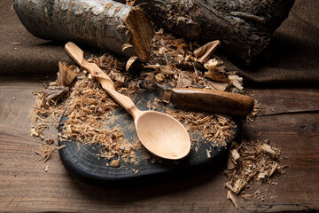 hand carved spoon with raw woods and carving tools