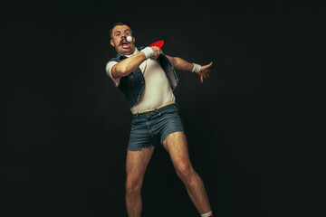 Young caucasian man playing tennis isolated on black studio background in retro style, action and motion concept