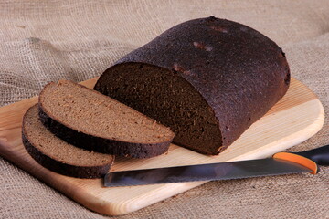 Fresh sliced rye bread loaf isolated on the wooden table and napkins - obrazy, fototapety, plakaty