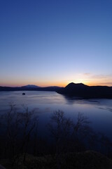 美しいグラデーションの夜明けの空と湖。日本の北海道の摩周湖。