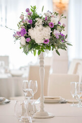 Centerpiece made of green leaves and fresh flowers stands on the dinner table. Wedding day. Fresh flowers decorations.