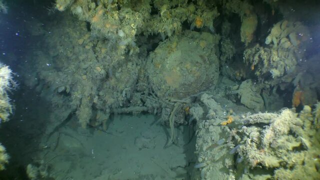 The camera slowly approaches the cover of the torpedo tube inside the sunken submarine.