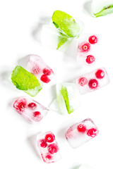 Obraz na płótnie Canvas mint and red berries in ice cubes white background top view