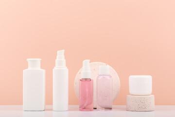 Set of skin care bottles with cosmetic products for skin care and beauty with geometric gypsum props against light orange background with copy space.  kin care products for cleaning, moisturizing and 