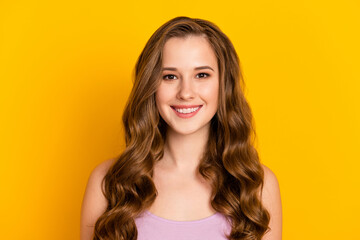 Photo of young happy cheerful smiling beautiful woman with long wavy brown hair isolated on yellow color background