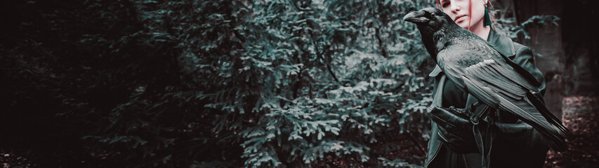 young woman or girl in the forest with a big black raven on his hand