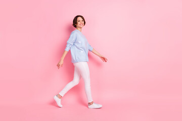 Fototapeta na wymiar Full size profile side photo of young charming lovely positive girl go walk wear blue sweater isolated on pink color background