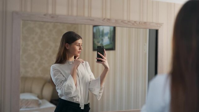 Portrait of a beautiful woman in the mirror taking pictures on a smartphone