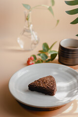 brownie on a white plate, a light orange background and a sunny morning coffee.