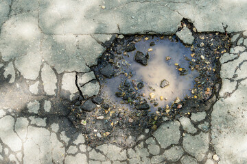 A puddle in a pit of asphalt of poor quality - a pothole in the asphalt as a result of poorly performed work