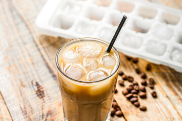 coffee break with cold iced latte and beans on wooden table background