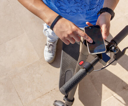 Young man using smartphone to unlock a shared electric scooter