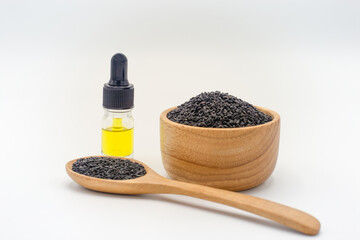 Sesame seeds in a wooden spoon And the extracted sesame oil is packed in a glass bottle.