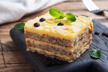 Banana sponge cake with nuts and chocolate drops. Delicious sweet dessert for tea, wooden background.