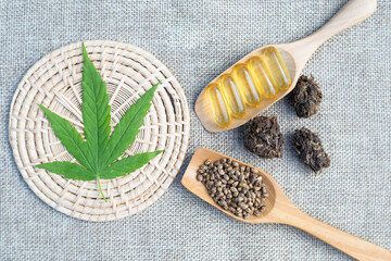 Cannabis leaves. Seeds and pills in a wooden spoon. Placed on a brown background. Cannabis and medical concept have text space.