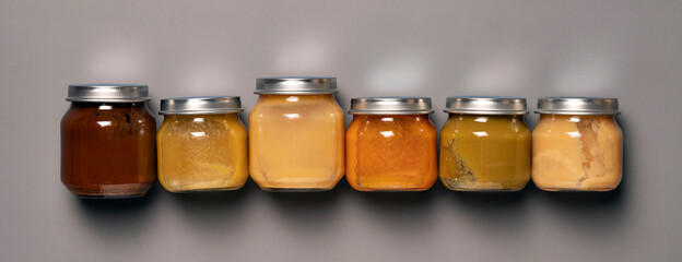 Banner. Glass jars with baby food in row. Baby puree. First feeding. Motherhood