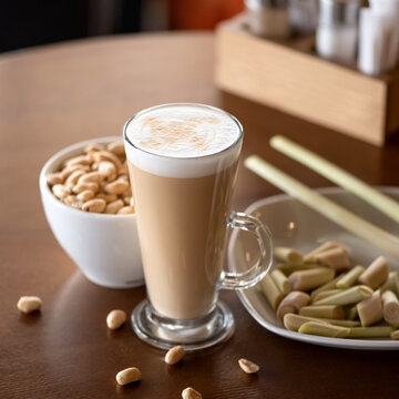 Glass of latte coffee with dessert. Frothy drink with sweet candies and peanuts. Light morning snack. Soft focus. Square format with copy space at top of image.