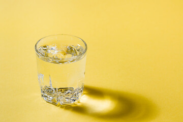A lonely glass of water in a yellow-gray palette. Loneliness and self-sufficiency concept. Copy space