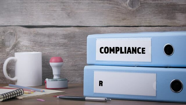 Compliance and Regulations concept. Office Binder on Wooden Desk