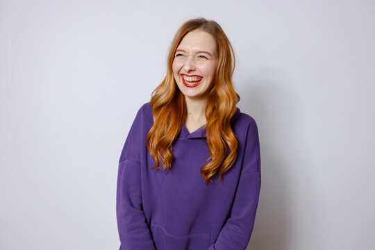 Funny redhead girl in purple hoodie. White background