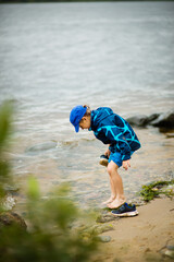 Little boy playing by the water, Freezing His feet, pouring water out of his shoe, Playing on the shore, Playing in the fresh air, selective focus