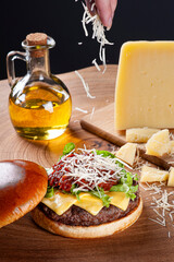 .Delicious beef burger with tomato sauce, parmesan cheese and lettuce on wooden table on dark background. Copy space