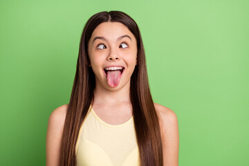 Portrait of excited carefree person squint eyes tongue out have fun isolated on green color...
