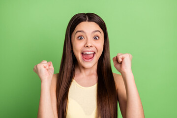 Photo of happy excited cheerful smiling little girl raise fists in victory success triumph isolated on green color background