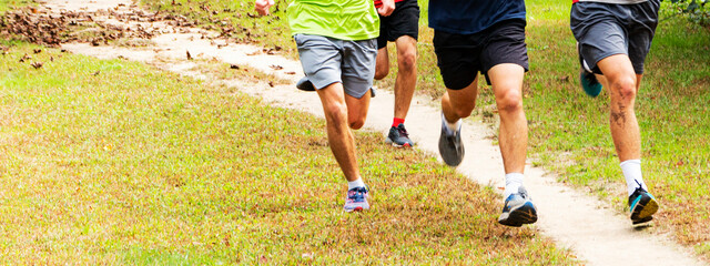 Obraz premium High school distance runners running together in a park with copy space on the left hand side