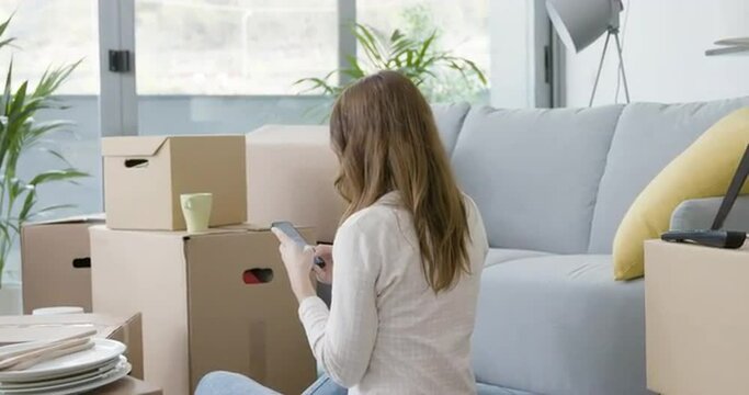 Woman chatting with her smartphone in her new home