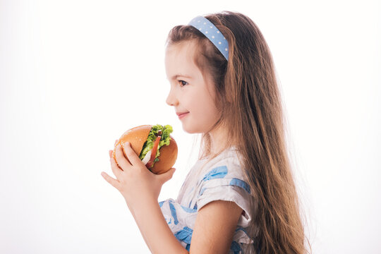 Little Girl Eating Big Burger. Kid Looking At Healthy Big Sandwich, Studio Isolated On White Background.