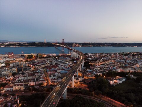 Aerial view of April 25th bridge with Christ the King statue (Cristo Rei) in background at sunset, view of Lisbon skyline at night, Alc&acirc;ntara, Lisbon, Portugal.