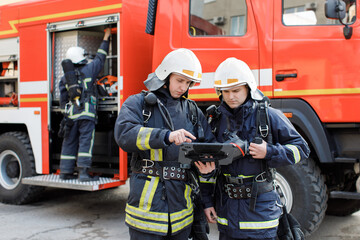 Portrait of two firefighters in fire fighting operation, fireman in protective clothing and helmet...