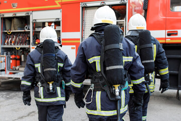 Fototapeta premium Portrait of firefighter in uniform in front of fire engine machine and fireman team