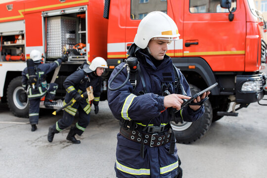 Portrait of firefighter in fire fighting operation, fireman in protective clothing and helmet using tablet computer in action fighting.