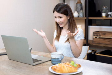 Happy beautiful Asian woman working on a laptop at home, Online video meetings with colleagues.